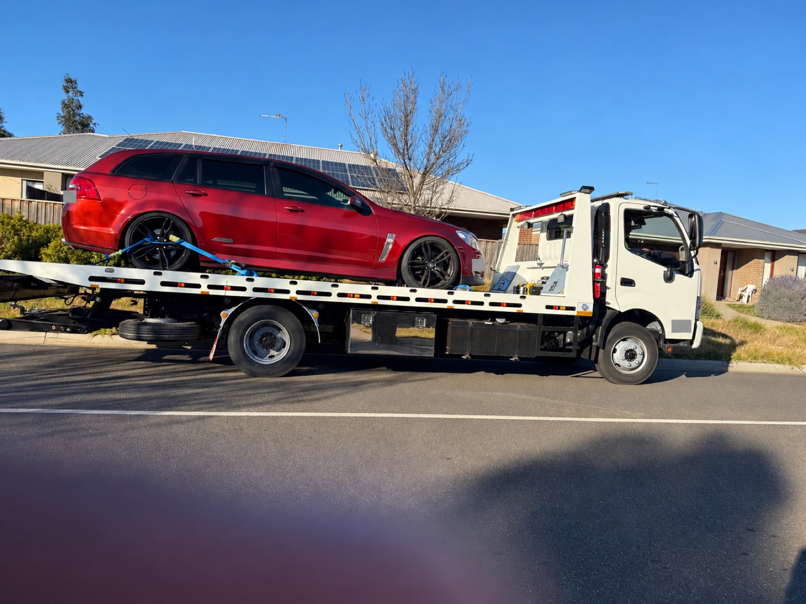 Red wagon on a flatbed tow truck; registration details obscured.